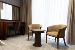 a room with two chairs and a table and a piano at Mir Luxe Plaza in Tashkent