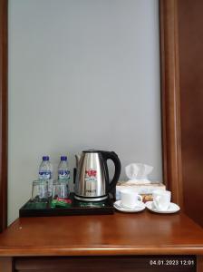 a coffee maker on a shelf with cups and water at Mir Luxe Plaza in Tashkent