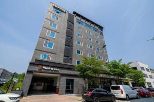 a tall building with cars parked in a parking lot at Wonju Central Hotel in Wonju