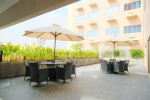 a patio with tables and chairs and umbrellas at Azana Asia Hotel Cilacap in Sidanegara
