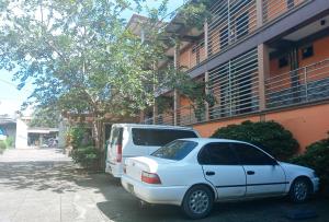 Ein weißer Van und ein weißer Van stehen neben einem Gebäude. in der Unterkunft IDMAT INN in Davao City