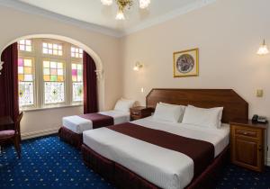 a hotel room with two beds and two windows at Palais Royale in Katoomba