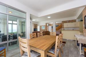 a dining room and kitchen with a wooden table and chairs at Vic Bay Beach House in Victoria Bay