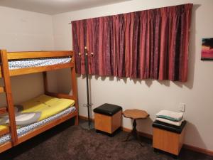 Airport accommodation في كرايستشيرش: غرفة نوم بسريرين بطابقين وستارة