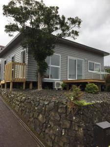 a house with a stone wall in front of it at Horizon View in Waihi Beach