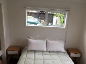 uma cama com duas almofadas num quarto com uma janela em Horizon View em Waihi Beach