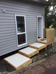 a house with wooden steps on the side of it at Horizon View in Waihi Beach