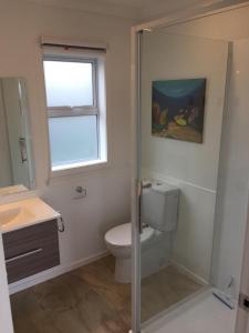 a bathroom with a toilet and a sink and a window at Horizon View in Waihi Beach