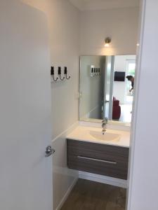 een badkamer met een wastafel en een spiegel bij Horizon View in Waihi Beach