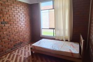 ein kleines Zimmer mit einem Bett in einer Ziegelwand in der Unterkunft La casa de Alex in Piura