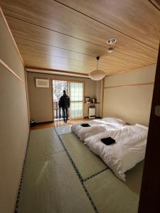 a man standing in a room with two beds at Lodge Seizan in Nozawa Onsen
