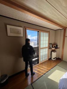 a person standing in a room looking out a window at Lodge Seizan in Nozawa Onsen