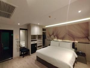 a bedroom with a white bed and a kitchen at Karnyapha Hotspring hotel in Ban Lum Than