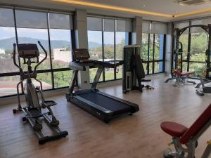 einen Fitnessraum mit Laufbändern und Crosstrainern in einem Zimmer mit Fenstern in der Unterkunft Karnyapha Hotspring hotel in Ban Lum Than
