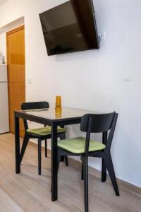 mesa de comedor con 2 sillas y TV en Apartments Mir - close to beach, en Duće