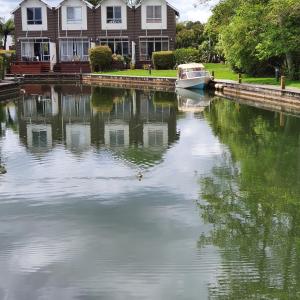 a boat docked in the water in front of a house at Kuituna on the Canal Villa, 3 bedrooms in Rotorua