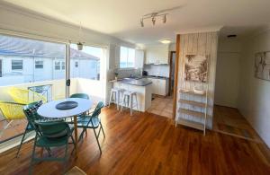 a living room with a table and chairs and a kitchen at Beachside Apartment Blackwoods Beach in Cronulla +17 photos