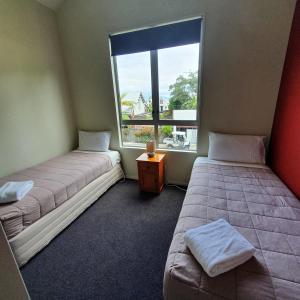 two beds in a room with a window at Kuituna on the Canal Villa, 3 bedrooms in Rotorua