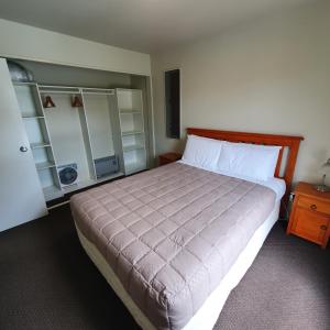 a bedroom with a large bed with a wooden headboard at Kuituna on the Canal Villa, 3 bedrooms in Rotorua