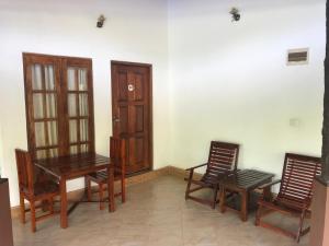 a room with three chairs and a table and a door at Paris Garden Resort in Trincomalee