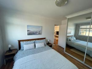 a bedroom with two beds and a mirror at Beachside Apartment Blackwoods Beach in Cronulla