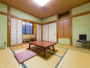 ein Wohnzimmer mit einem Tisch und einem TV in der Unterkunft 池の平温泉 ロッジ コクハ in Myōkō
