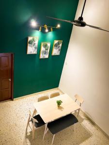 einen Tisch und Stühle in einem Zimmer mit grüner Wand in der Unterkunft Lake View 53 Heritage by LOUIS in Taiping
