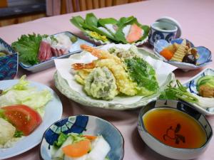 una mesa con platos de comida y tazones de sopa en 池の平温泉 ロッジ コクハ, en Myoko