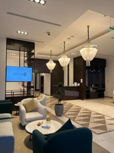 un vestíbulo con sillas y una pantalla en un edificio en Hotel ALdoliaa en Unayzah