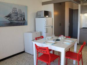 een keuken met een witte tafel en rode stoelen bij Appartement Port-la-Nouvelle, 2 pièces, 4 personnes - FR-1-229C-26 in Port-la-Nouvelle