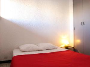 een slaapkamer met een rood en wit bed met 2 kussens bij Appartement Port-la-Nouvelle, 2 pièces, 4 personnes - FR-1-229C-26 in Port-la-Nouvelle