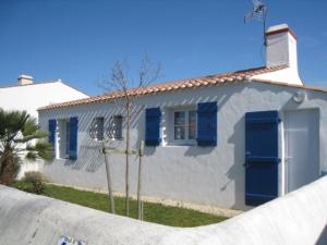 uma casa branca com persianas azuis e uma cerca em Maison L'Épine, 3 pièces, 5 personnes - FR-1-224B-515 em LʼÉpine