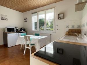a kitchen with a table and a counter top at Maison avec Jardin Clos près de la Plage - 5 Couchages, 3 Étoiles, Ménage Inclus - FR-1-224B-474 in Barbâtre +8 photos