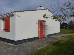 ein weißes Gebäude mit roten Türen und einem Hof in der Unterkunft Maison Bretignolles-sur-Mer, 2 pièces, 4 personnes - FR-1-224A-586 in Brétignolles-sur-Mer