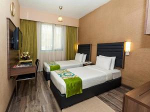 a hotel room with two beds and a television at Oasis Deira Hotel in Dubai