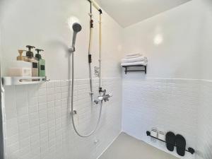 a bathroom with a shower with white tiles at attomi hostel in Sapporo