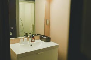a bathroom with a white sink and a mirror at LIBERATED HOTEL Haruyoshi Kaichi in Fukuoka +14 photos