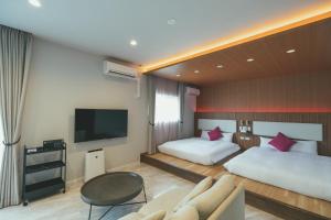 福岡市にあるLiberated HOTEL 春吉開地のベッド2台とテレビが備わるホテルルームです。