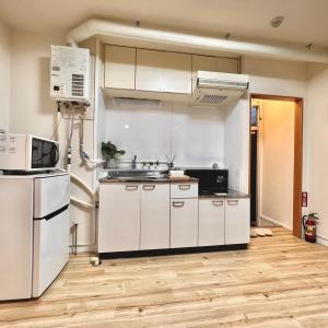 an empty kitchen with white cabinets and a microwave at attomi hostel in Sapporo