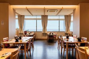 un restaurante con mesas, sillas y ventanas grandes en KAMENOI HOTEL Chitamihama en Mihama