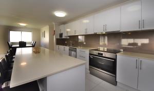 a kitchen with white cabinets and a white counter top at Holiday Home in Koonawarra in Dapto