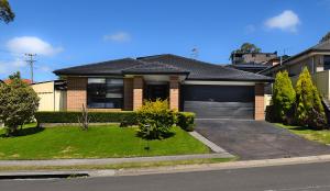 a brick house with a garage and a driveway at Holiday Home in Koonawarra in Dapto