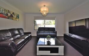 a living room with a leather couch and a table at Holiday Home in Koonawarra in Dapto