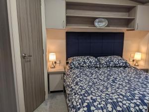 a bedroom with a bed and a blue headboard at Modern 2 Bedroom Mobile home with parking on St Helens Coastal Resort Isle of Wight in Saint Helens