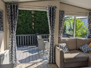 un porche cubierto con sofá y sillas en Modern 2 Bedroom Mobile home with parking on St Helens Coastal Resort Isle of Wight en Saint Helens