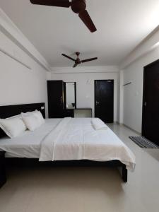 a bedroom with a white bed with a ceiling fan at Alohaa Homestel in Coimbatore