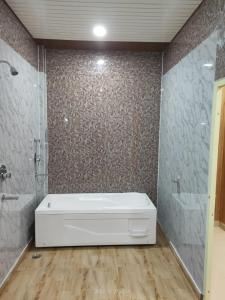 a bathroom with a white tub and a shower at Kyarki Resort in Rishīkesh
