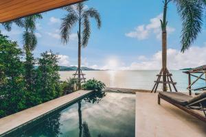 a pool with palm trees and a view of the water at Allure Resort in Choeng Mon Beach