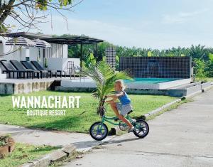 a young child riding a bike down a sidewalk at Wannachart Boutique Resort in Tha Sala