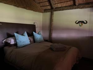 a bedroom with a large bed with blue pillows at Vilagama Game Lodge in Naboomspruit